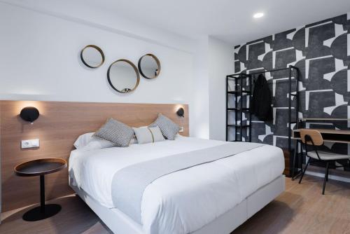 a bedroom with a large white bed and a desk at Smartr Valencia Turia in Valencia