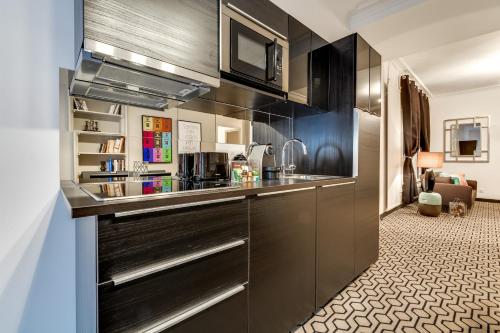 - une cuisine avec des placards noirs et un évier dans l'établissement Sweett - Paix, à Paris