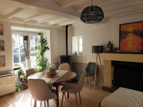 a living room with a table and chairs and a fireplace at Maison de charme avec terrasse in Ver-sur-Mer