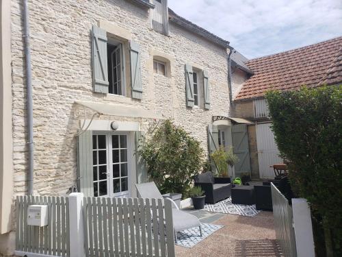 a white fence in front of a house at Maison de charme avec terrasse in Ver-sur-Mer