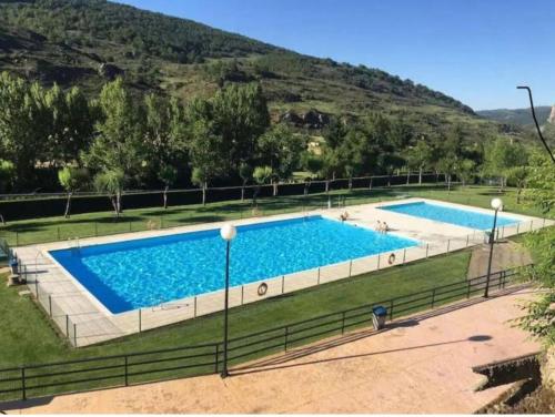 two swimming pools in a field with a hill in the background at Ezcaray Pet Friendly, piscina y parking in Zorraquín