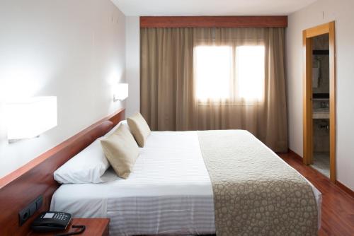 a bedroom with a large white bed and a window at Catalonia Park Putxet in Barcelona