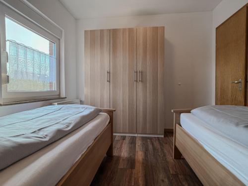 two beds in a room with a window at FeWo Oldeoog OG - Horumersiel in Horumersiel
