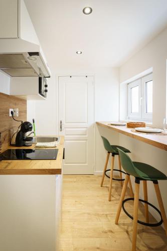 une cuisine avec des placards blancs et un comptoir avec des chaises vertes dans l'établissement Stud Sauge 2pers wifi city centre, à Cambrai