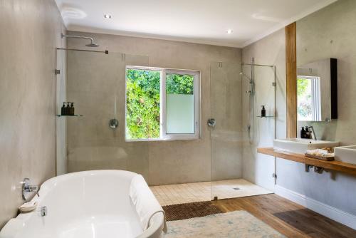 a bathroom with a tub and a shower and a sink at Angala in Simondium