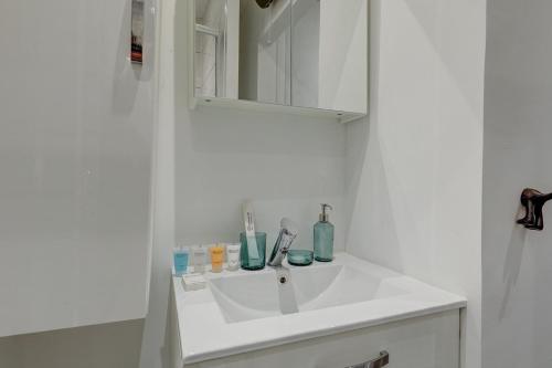 une salle de bain blanche avec un lavabo et un miroir dans l'établissement 587 Suite Stuart - Superb apartment in Paris, à Paris