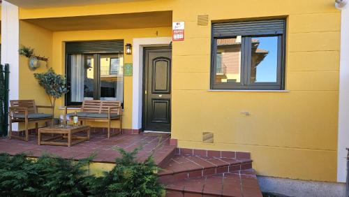 a yellow house with two chairs and a door at Casa Arenal COMILLAS, grande, céntrico y tranquilo, con jardín y piscina, ideal para familias in Comillas