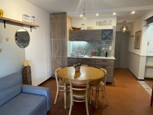 une cuisine et une salle à manger avec une table et un canapé bleu dans l'établissement Le 45- La Sauvagine, Appartement avec grande terrasse, 6 Couchages, 2 chambres, 3min de la plage, à Saintes-Maries-de-la-Mer