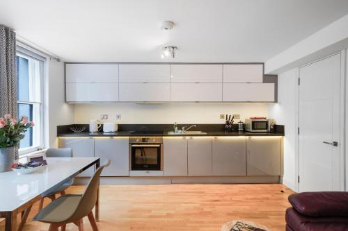 a kitchen with white cabinets and a dining table at Apt 3, Soho Apartments 2nd & 3rd floors by Indigo Flats in London