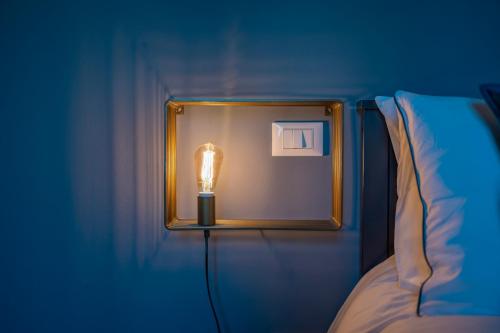 a light on a wall next to a bed at LaMalatestina Suite - Apartment in front of the Castle in Rimini