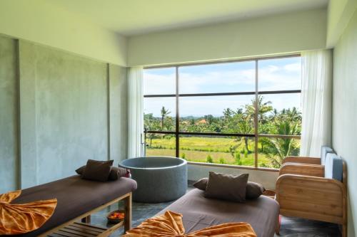 a room with two beds and a large window at Emana Akatara in Ubud