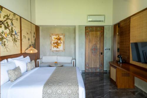 a bedroom with a large white bed and a television at Emana Akatara in Ubud