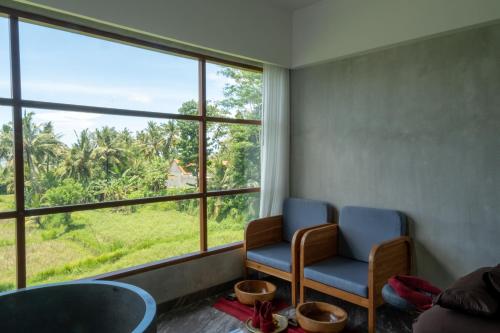 a waiting room with two chairs and a large window at Emana Akatara in Ubud