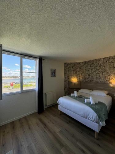 a bedroom with a large bed and a large window at Couett'Hôtel Brest Port de plaisance, Les pieds dans l'eau in Brest