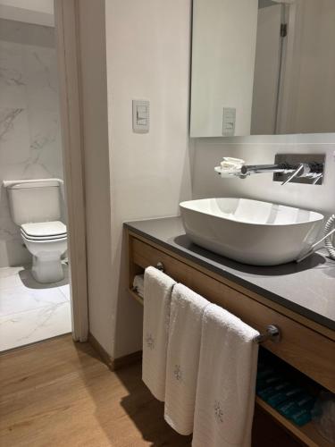 a bathroom with a sink and a toilet with towels at Hotel Estilo MB - Mar del Plata in Mar del Plata