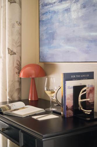 a desk with a lamp a wine glass and a book at Townhouse on the Green in Dublin