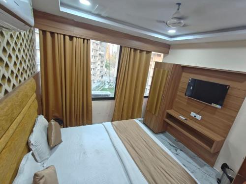 a bedroom with a bed and a flat screen tv at Hotel Royal King in Ahmedabad