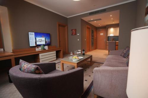 a living room with two couches and a flat screen tv at Divan Erbil Hotel in Erbil