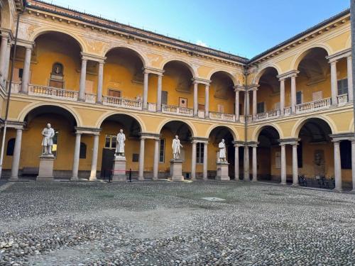 a large yellow building with statues in the courtyard at Università & Strada Nuova - Lovely Suite Scaldasole in Pavia