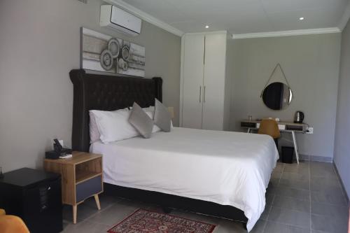 a bedroom with a large white bed and a desk at Boksburg Hotel in Boksburg