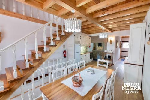 Una cocina y un comedor con una mesa y una escalera. en Casa do Morro by PontaNegraAzores, en Agualva