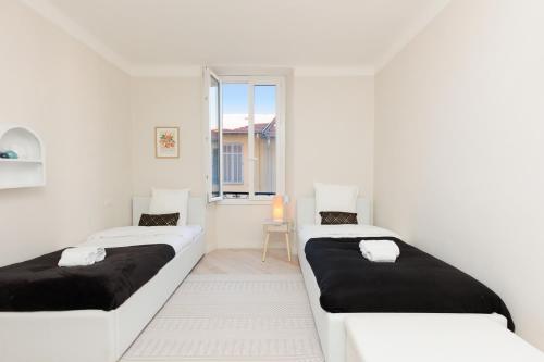 deux lits dans une chambre blanche avec une fenêtre dans l'établissement Perrissol YourHostHelper, à Cannes