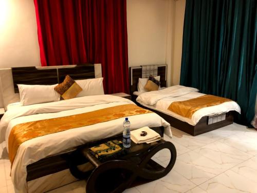 a hotel room with two beds and a table at Hotel Malamjabba Palace by Khan Familia Travels in Swat