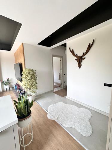 a living room with a white wall with a deer head on the wall at Marina ve sayapark avm yakın iki odalı tasarımlı güzel ev in Mersin