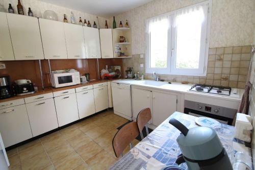 une cuisine avec des armoires blanches, une table et une fenêtre dans l'établissement Maison 5 pièces 6 couchages Saint Georges d'Oléron SGO000-684, à Saint-Georges-dʼOléron