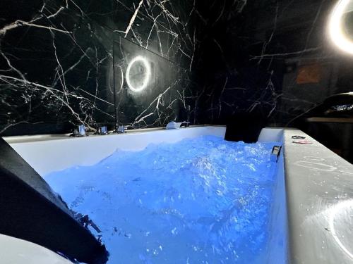 - une baignoire remplie d'eau bleue dans la chambre dans l'établissement Un cocon paisible avec Balnéo proche centre ville, à Reims