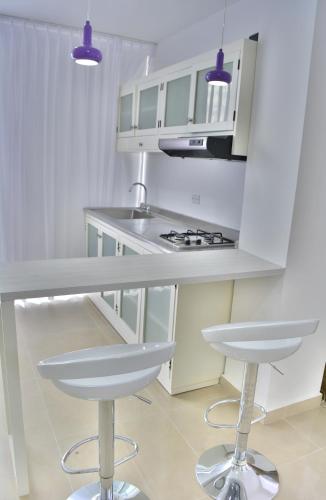 a white kitchen with white cabinets and stools at Monterosa Apartamentos Amoblados in Pereira