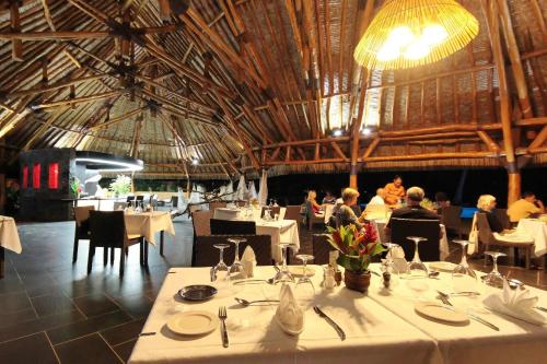 a dining room with white tables and people in a building at Maitai Lapita Village Huahine in Fare