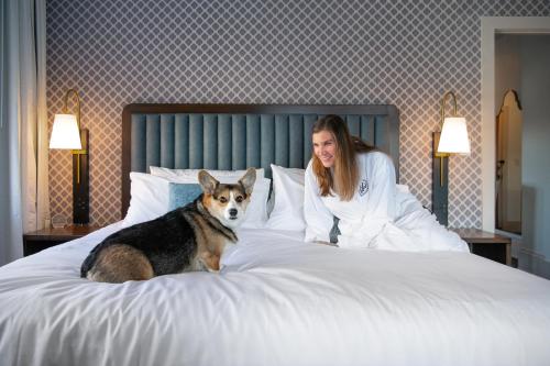 a woman sitting on a bed with a dog at Hotel Petersburg, Tapestry Collection By Hilton in Petersburg