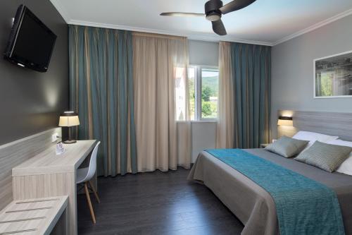 a hotel room with a bed and a desk and a television at Hotel Combarro in Combarro