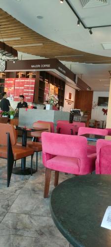 a restaurant with pink chairs and tables in a room at Your House Quy Nhơn FLC in Quy Nhon