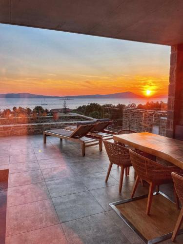 a patio with tables and chairs and a sunset at Gialova SUNSET VILLA with Seaview & Private Pool in Gialova