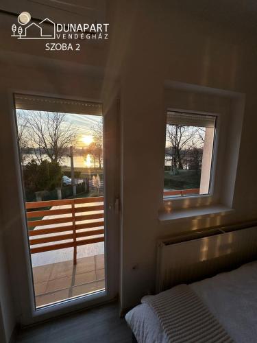 a bedroom with a window with a view of a balcony at Dunapart Vendégház Esztergom in Esztergom