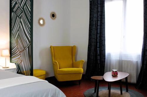 - une chambre avec une chaise jaune et une table dans l'établissement Appartement Centre Historique, à LʼIsle-sur-la-Sorgue