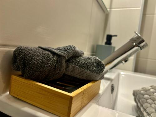 - une boîte en bois avec des serviettes et un lavabo dans la salle de bains dans l'établissement Joyeuse Escale à la Gare - 368, à Rouen