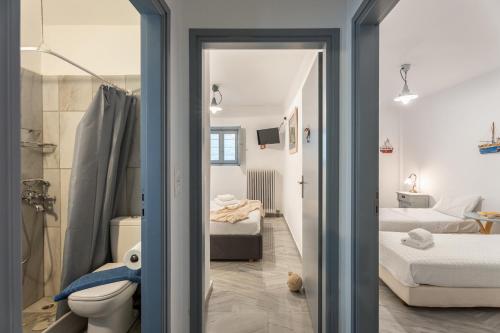 a bathroom with a toilet and a bedroom with two beds at Villa Vireya in Naousa