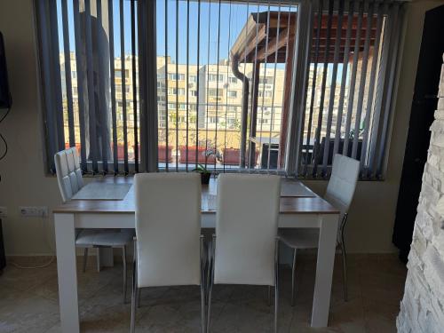 a dining room table with white chairs and a large window at Apartment near Vitosha mountain, self check-in, with underground parking in Sofia