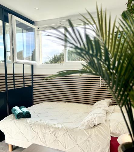 - un lit blanc dans une chambre avec un palmier dans l'établissement La Gravière, Cozy Studio Wifi & Parking 20M Océan Surf Plage, à Soorts-Hossegor