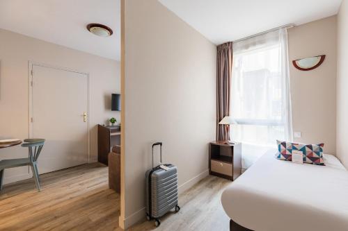 a hotel room with a bed and a suitcase at Appart'City Confort Agen Centre in Agen