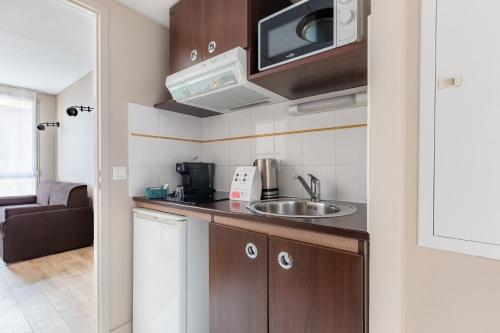 a small kitchen with a sink and a microwave at Appart'City Confort Agen Centre in Agen