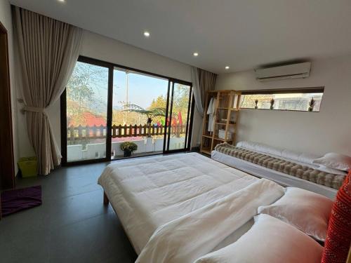 a bedroom with two beds and a large window at Én Nhỏ Homestay Sa Pa in Sa Pa