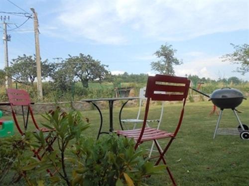 two chairs and a barbecue grill in a yard at Gîte Vacances en Auvergne in Saint-Géron