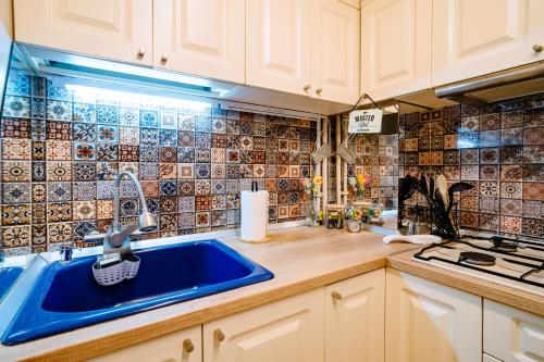 a kitchen with a blue sink and tiles on the wall at The QUARK Modern Designed 2BR Central Apartment in Craiova