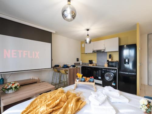 un salon avec un écran de projection et une cuisine dans l'établissement Au Charme Lyonnais classé 3 etoiles, à Vénissieux