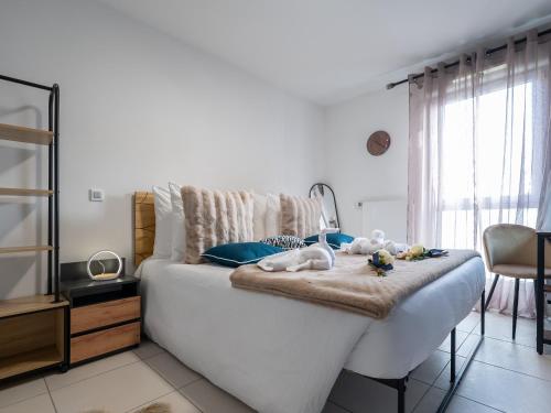 Un dormitorio con una gran cama blanca con toallas. en Au Charme Lyonnais classé 3 etoiles, en Vénissieux