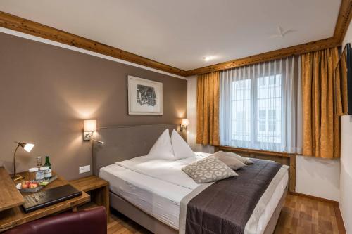 a bedroom with a bed and a desk and a window at Hotel Stern Chur in Chur